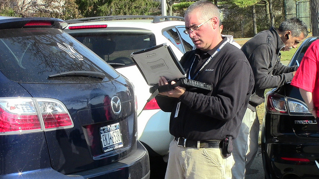Insurance claims adjuster inspecting SUV vehicle and making notes.