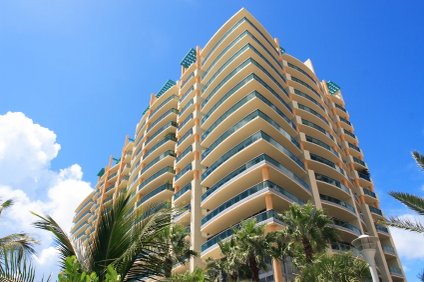 Condominium Building with many units and palm trees and beautiful weather, clouds