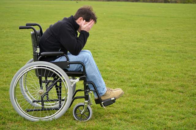 Man in wheelchair who seems stressed or sad