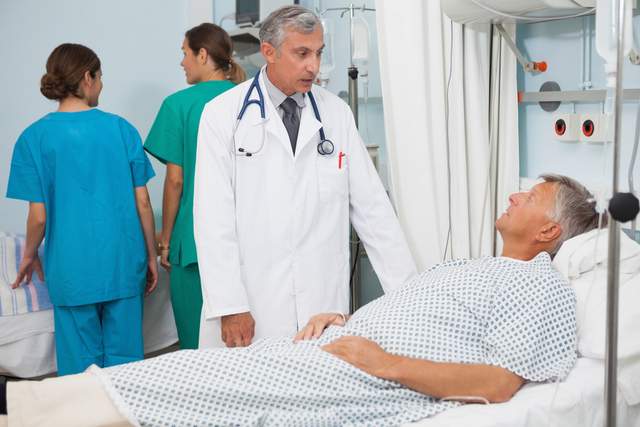 Man laying in hospital bed talking to doctor