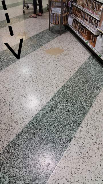 Arrow pointing to beige puddle of liquid on the floor of a Florida supermarket.