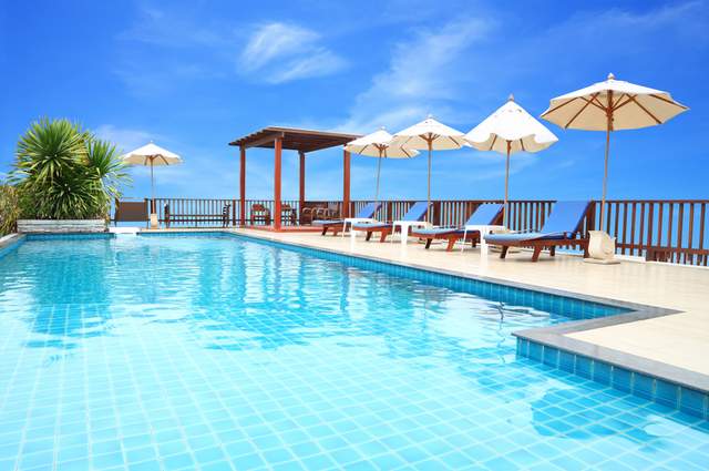 Outdoor swimming pool with deck chairs, gazebo and umbrellas.