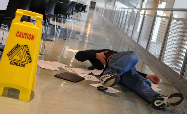 Hurt, lying on floor next to caution sign