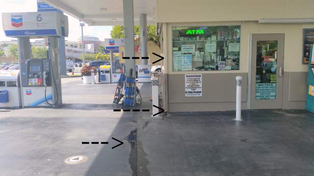 Rain gutter at Chevron gas station. Water on walkway.