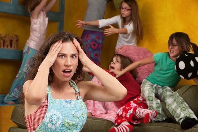 Day care woman who is overwhelmed by kids standing on sofa and shelf and playing