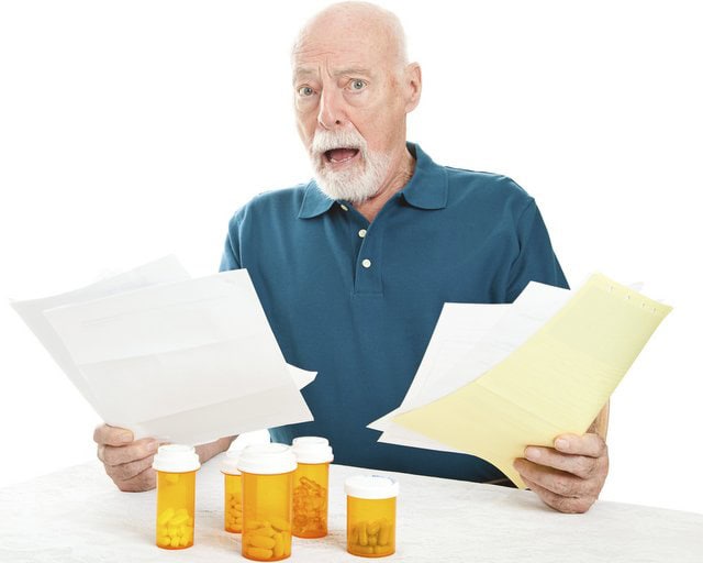 Man Stressed Holding Bills. Nex to Prescription bottles.