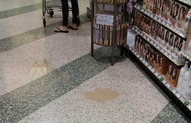 Beige liquid on the supermarket sales floor. Next to a shopper.