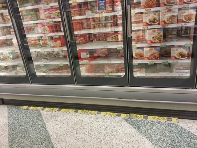 warning absorbable strip in front of refrigerator at supermarket