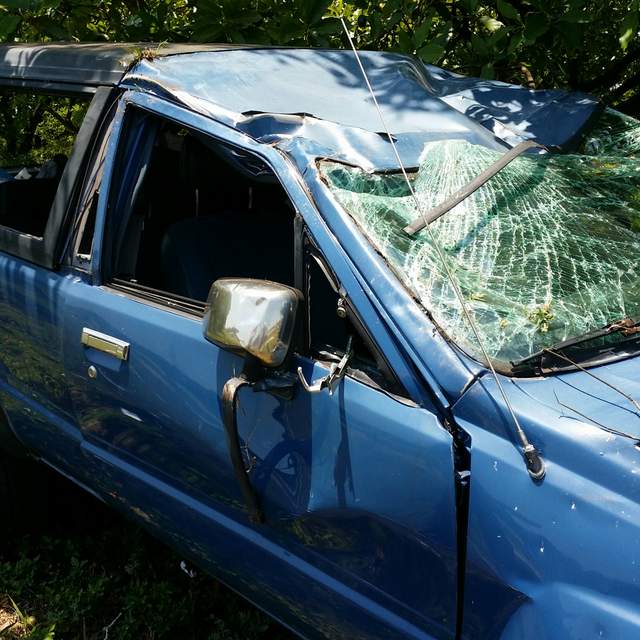 Truck with smashed winshield and dented roof after rollover crash