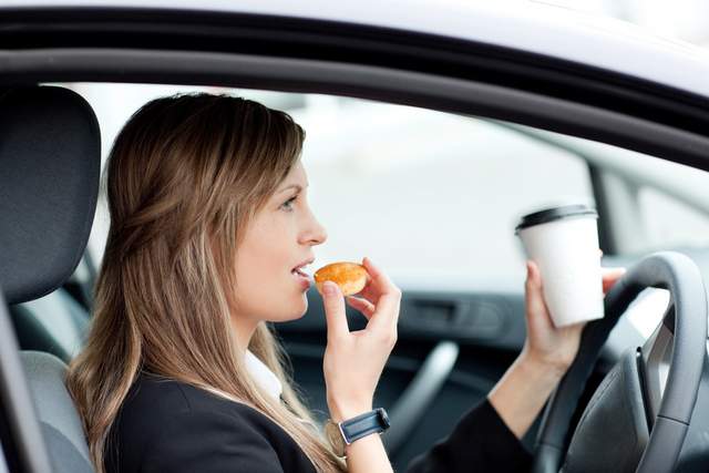 Eating food and holding cup of cofee while driving
