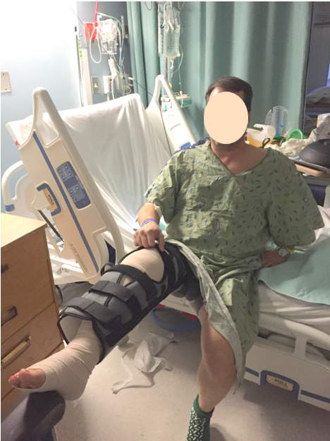patient in hospital room with bandage and brace on his leg