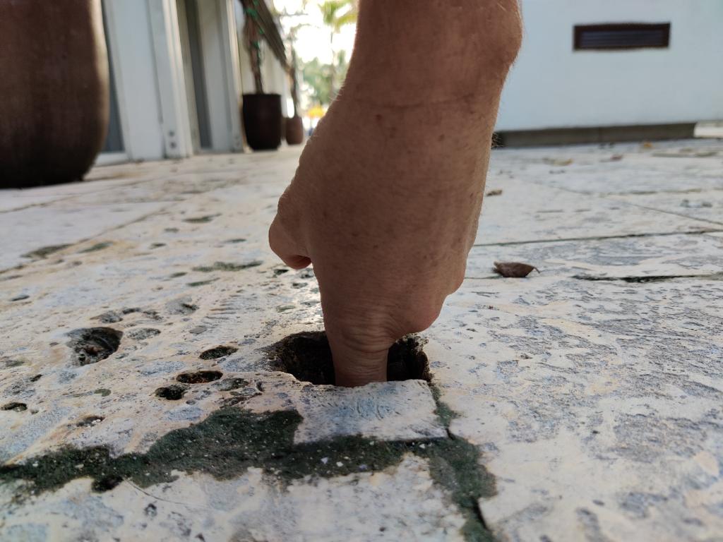 finger inside a deep hole in walkway tile at a hotel 