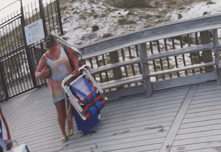 woman holding a football and beach chairs on a beach hotel boardwalk