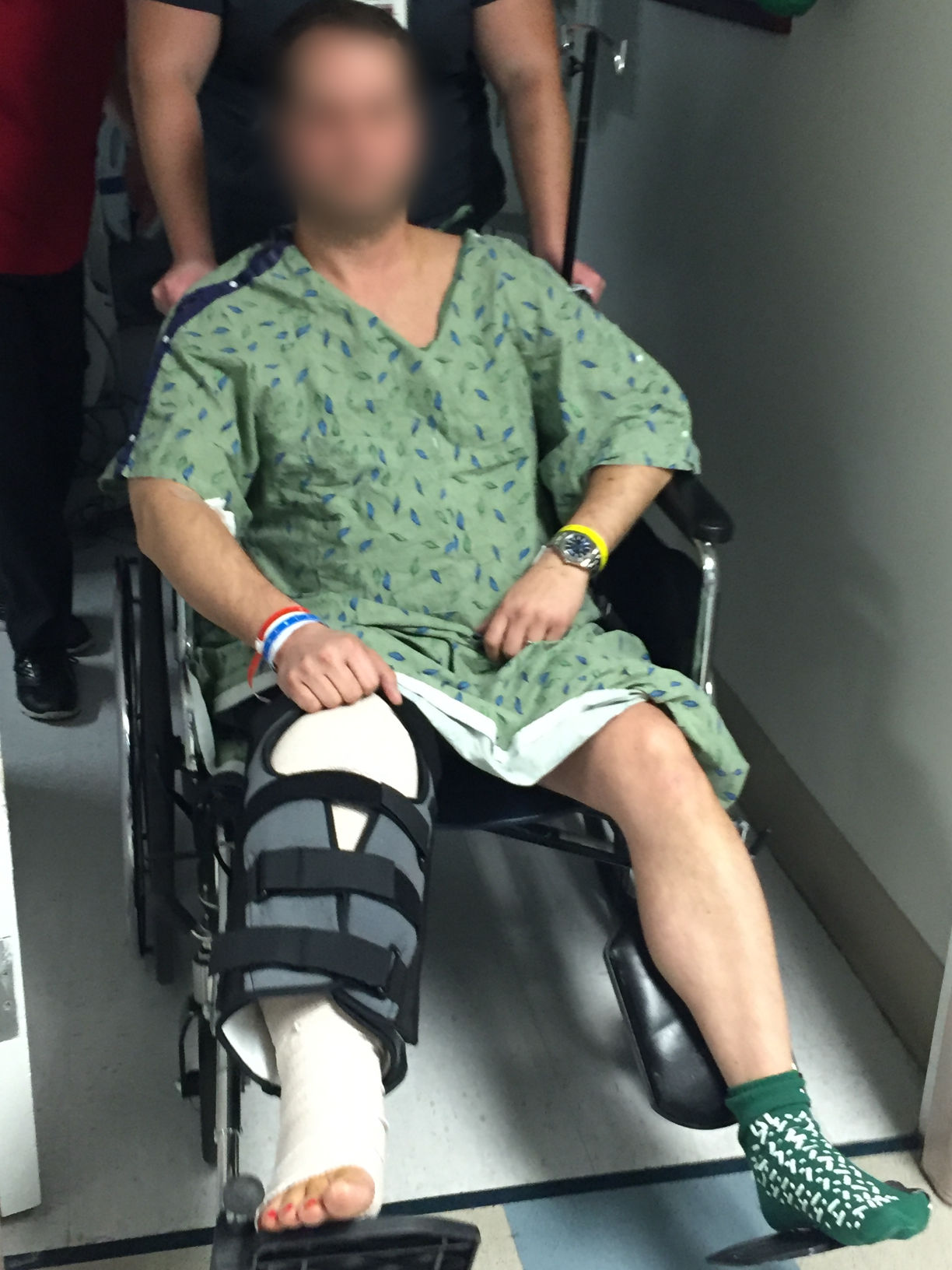 patient in wheelchair with brace on leg being wheeled 
