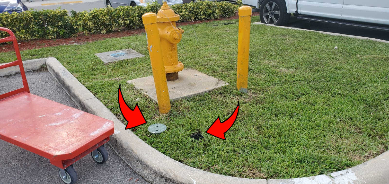 arrows pointing at the cover of an irrigation control valve laying in the grass, next to the uncovered irrigation control valve.  